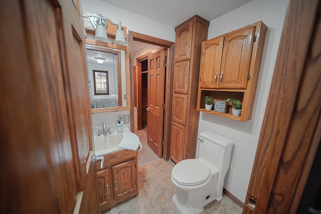 bathroom featuring toilet, baseboards, and vanity