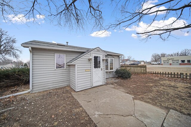 rear view of house with fence and an outdoor structure