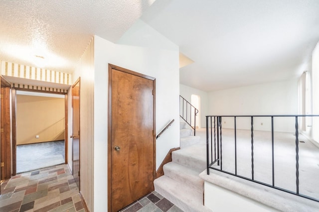 stairs featuring carpet and a textured ceiling