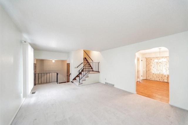 carpeted empty room with a chandelier