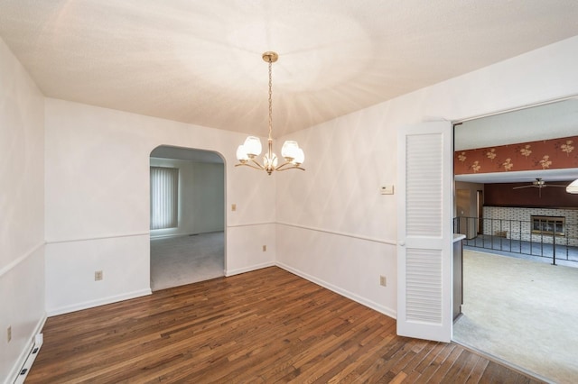 unfurnished room with baseboard heating, dark hardwood / wood-style floors, and a chandelier