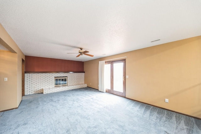 unfurnished living room featuring ceiling fan, a brick fireplace, carpet, and a textured ceiling