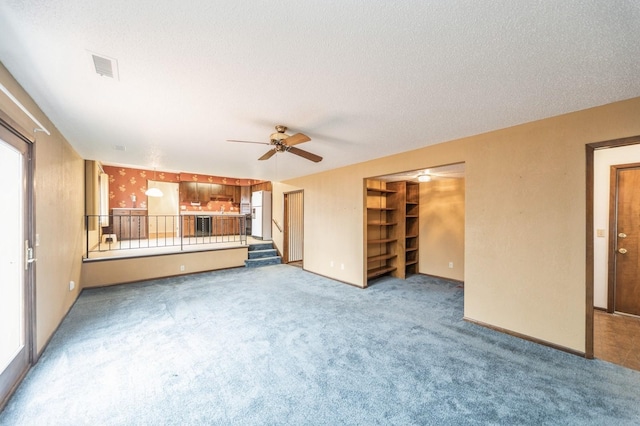 unfurnished living room with ceiling fan, carpet floors, and a textured ceiling