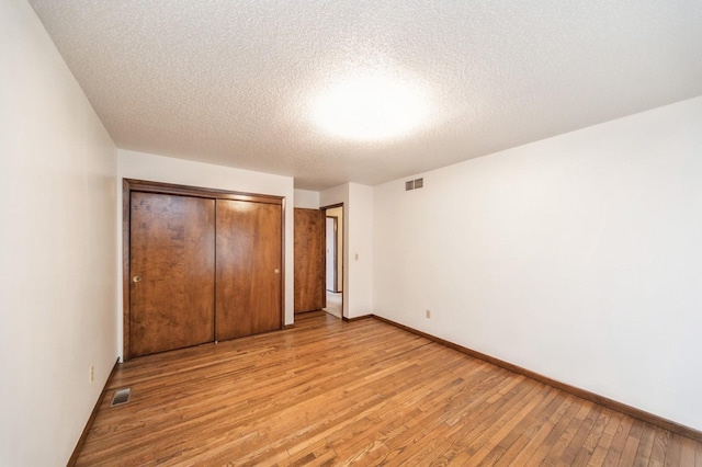 unfurnished bedroom featuring a closet, light hardwood / wood-style flooring, and a textured ceiling