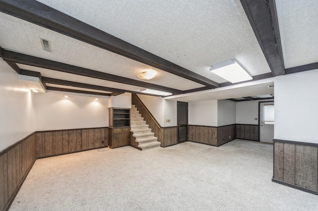 basement with light carpet, a textured ceiling, and wood walls