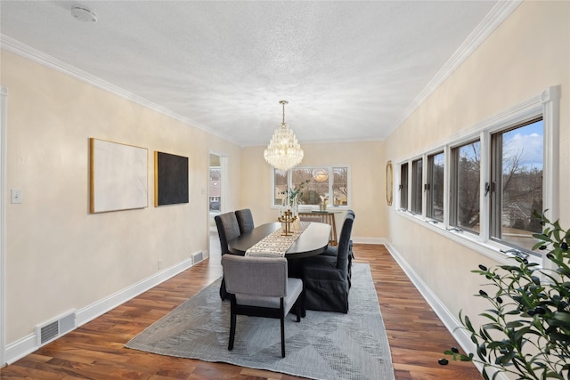 dining area with dark wood-type flooring, ornamental molding, a textured ceiling, and a notable chandelier