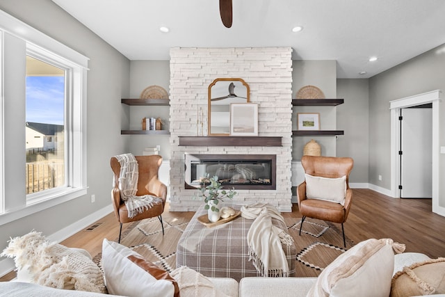 living room with hardwood / wood-style floors and a stone fireplace