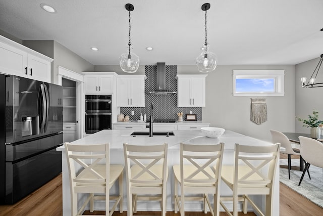 kitchen with double wall oven, tasteful backsplash, black fridge with ice dispenser, light wood-style floors, and wall chimney exhaust hood