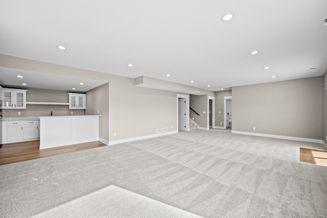 unfurnished living room featuring light colored carpet and indoor bar