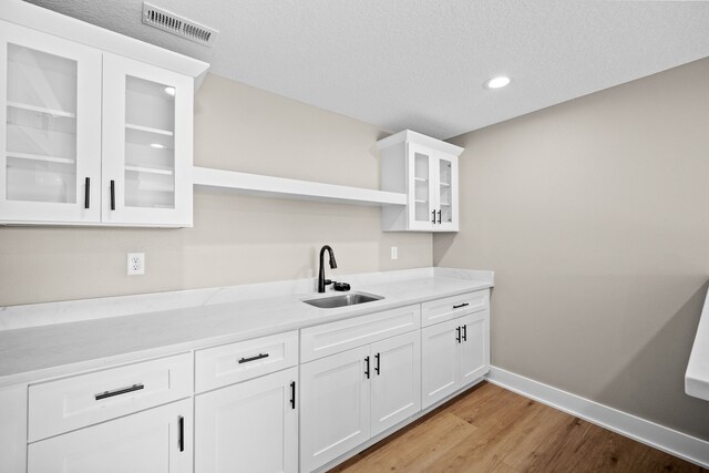 kitchen with a sink, visible vents, baseboards, light wood-type flooring, and open shelves