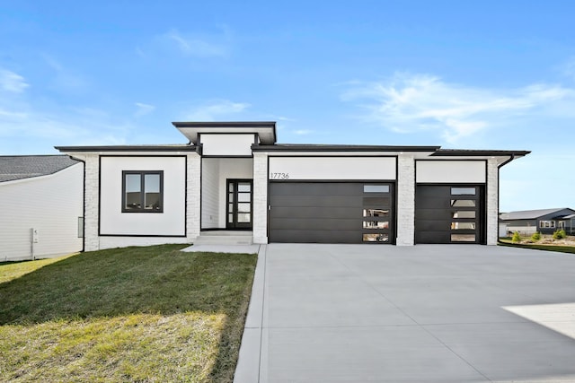 view of front of property with driveway, stucco siding, an attached garage, and a front yard