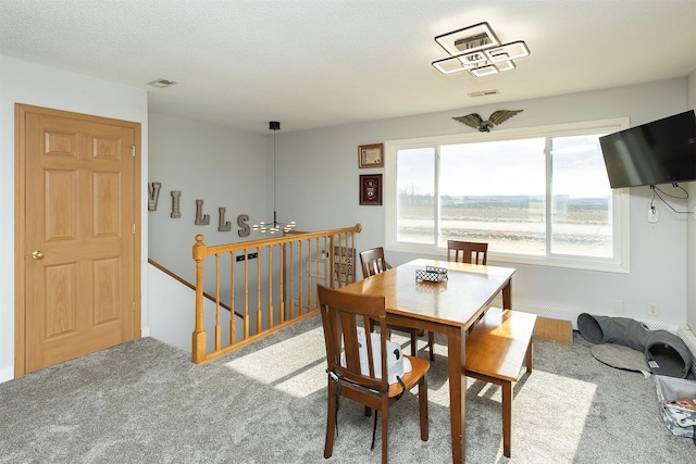 carpeted dining room featuring visible vents and a textured ceiling