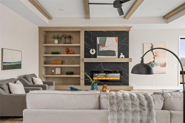 living room featuring hardwood / wood-style flooring, built in features, ceiling fan, beam ceiling, and a high end fireplace