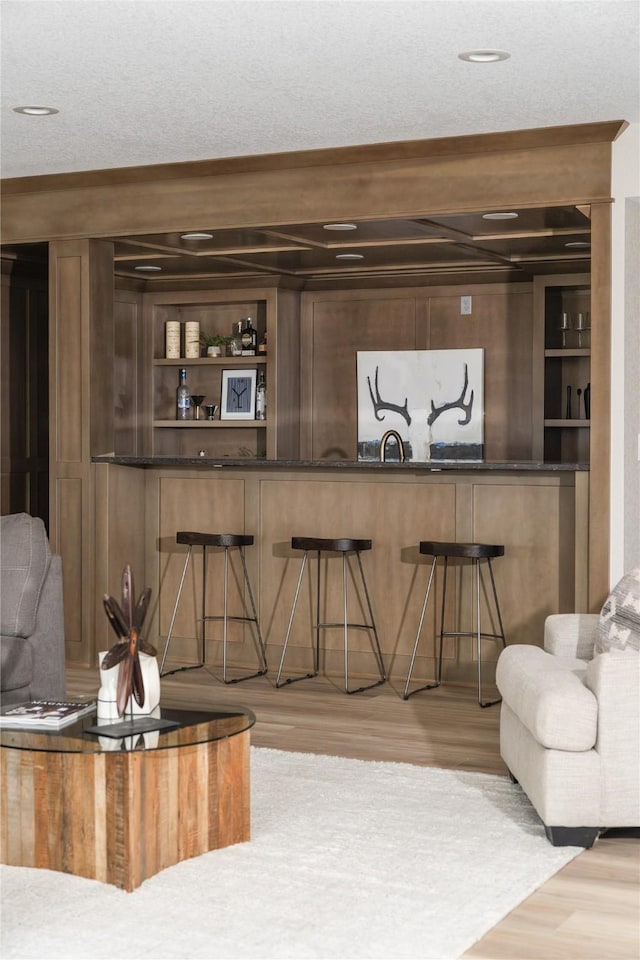 living room with built in shelves, wet bar, and light wood-type flooring