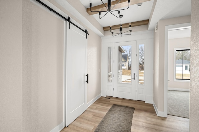 entrance foyer featuring a barn door, plenty of natural light, an inviting chandelier, and light wood-type flooring