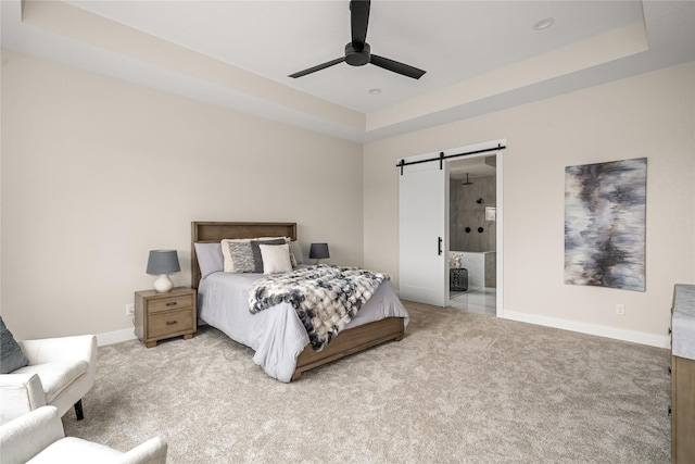 carpeted bedroom with ceiling fan, ensuite bath, a barn door, and a raised ceiling