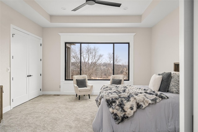 carpeted bedroom featuring ceiling fan and a raised ceiling