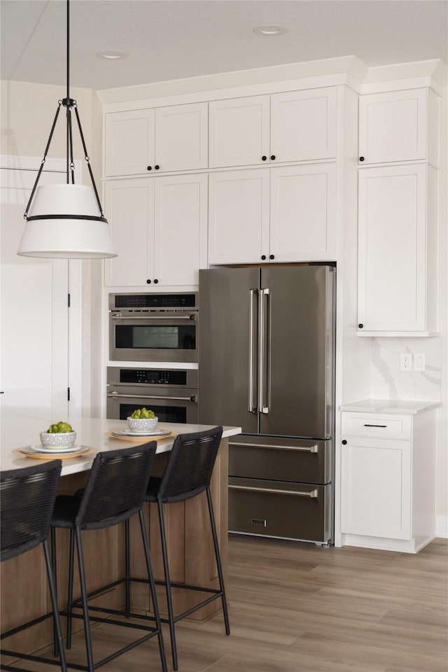 kitchen with white cabinetry, stainless steel appliances, dark hardwood / wood-style floors, and a breakfast bar