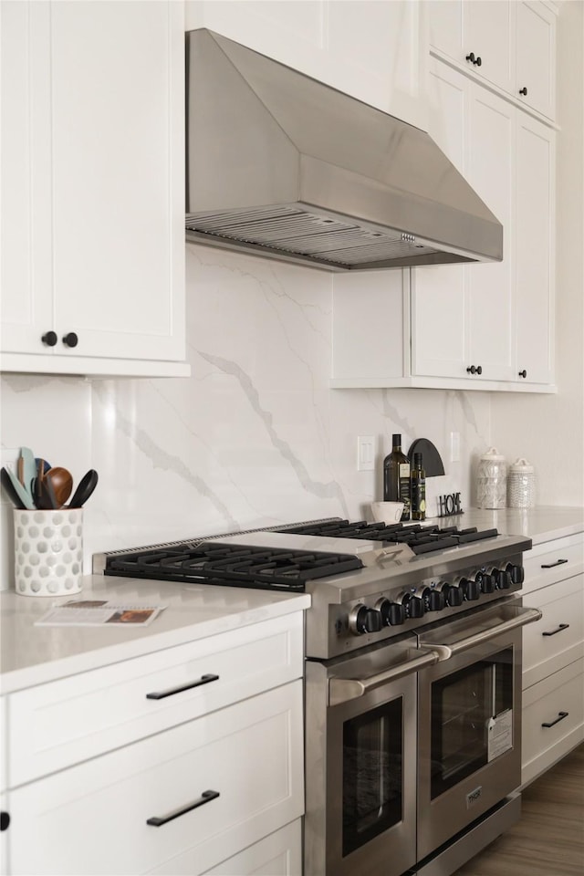 kitchen featuring white cabinets, dark hardwood / wood-style flooring, decorative backsplash, double oven range, and wall chimney range hood