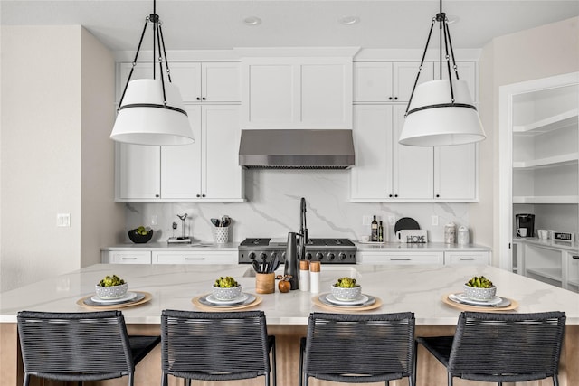 kitchen featuring wall chimney range hood, a kitchen breakfast bar, white cabinets, and a kitchen island