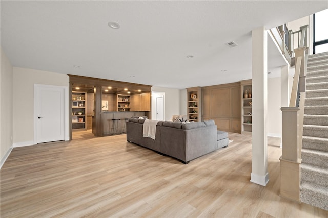 unfurnished living room with built in shelves and light hardwood / wood-style floors