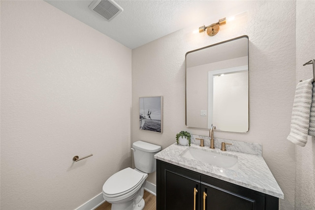 bathroom featuring hardwood / wood-style flooring, vanity, a textured ceiling, and toilet