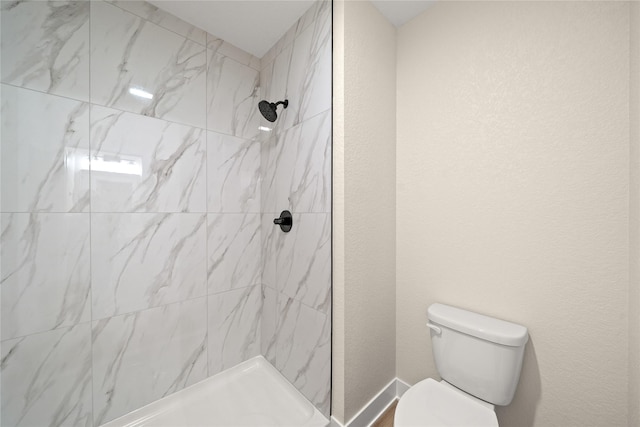 bathroom featuring tiled shower and toilet