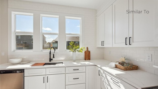 kitchen with tasteful backsplash, dishwasher, sink, and white cabinets