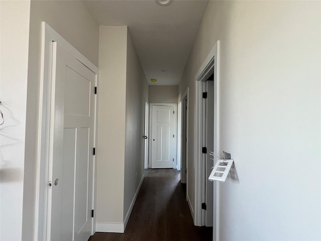 hall with baseboards and dark wood finished floors
