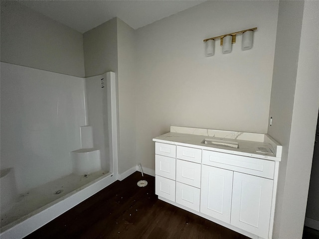 bathroom featuring walk in shower, vanity, baseboards, and wood finished floors