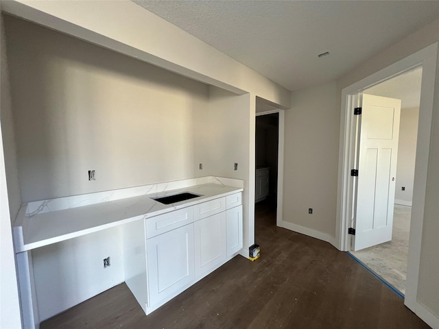 interior space with dark wood finished floors, baseboards, and a sink