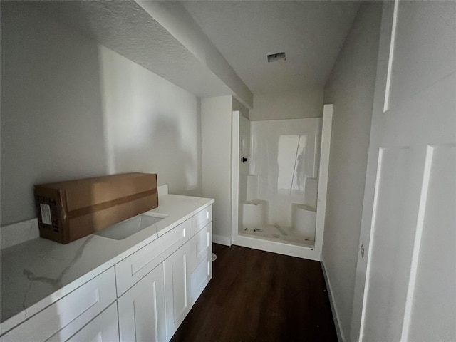 bathroom featuring vanity, a walk in shower, baseboards, and wood finished floors