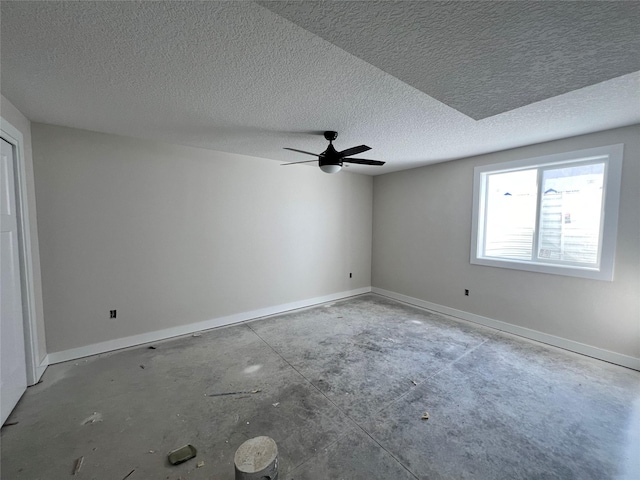 empty room with baseboards, a textured ceiling, concrete floors, and a ceiling fan