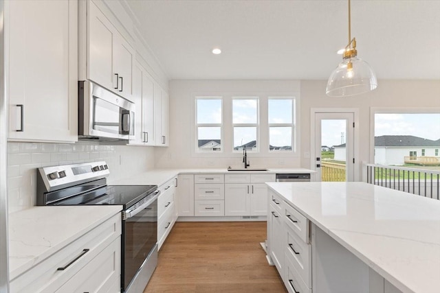 625 NW Georgetown Dr, Waukee, IA 50263 - kitchen featuring appliances with stainless steel finishes, white cabinets, healthy amount of natural light, light stone counters, and recessed lighting