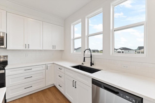 625 NW Georgetown Dr, Waukee, IA 50263 - kitchen with appliances with stainless steel finishes, tasteful backsplash, white cabinetry, light wood finished floors, and light stone counters