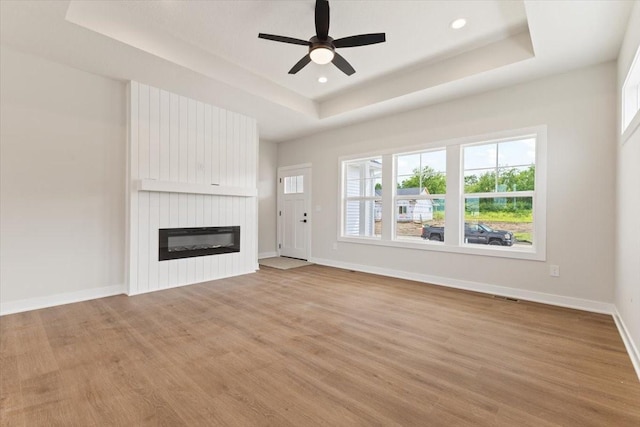 625 NW Georgetown Dr, Waukee, IA 50263 - unfurnished living room with a tray ceiling, light wood-type flooring, a fireplace, ceiling fan, and recessed lighting