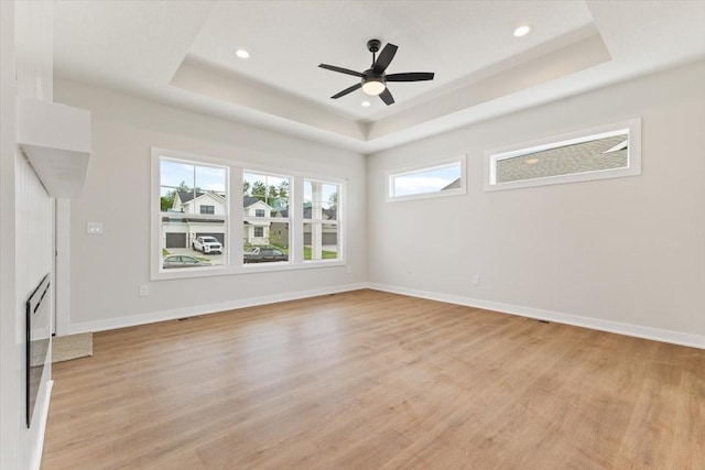 625 NW Georgetown Dr, Waukee, IA 50263 - unfurnished living room featuring a raised ceiling, light wood finished floors, a ceiling fan, and recessed lighting