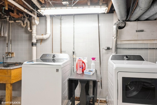 laundry room with tile walls, sink, and washer and dryer