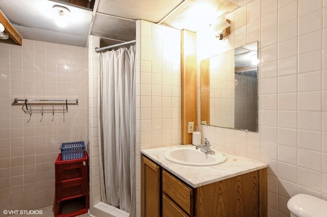 bathroom with vanity, toilet, a shower with shower curtain, and tile walls