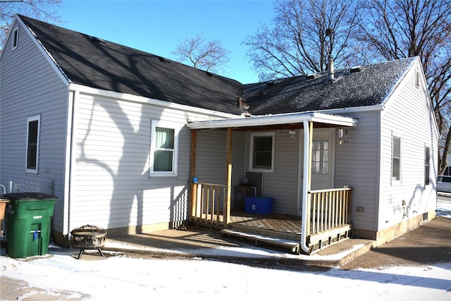 snow covered property featuring covered porch and an outdoor fire pit