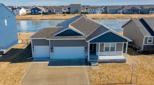 view of front facade with a garage, a porch, and a water view