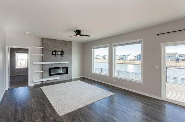 unfurnished living room with ceiling fan, a large fireplace, dark hardwood / wood-style floors, and built in features