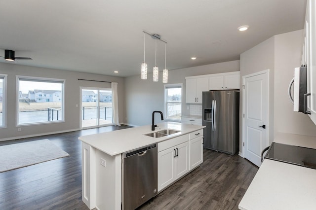 kitchen featuring white cabinetry, sink, hanging light fixtures, stainless steel appliances, and a center island with sink