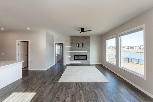 unfurnished living room featuring a water view, dark hardwood / wood-style floors, and a fireplace