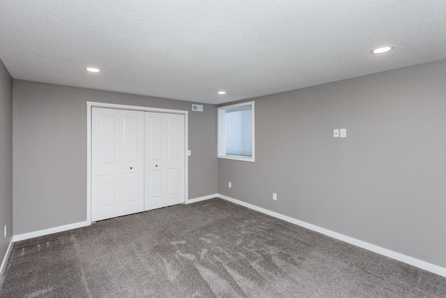 unfurnished bedroom with a closet, dark carpet, and a textured ceiling