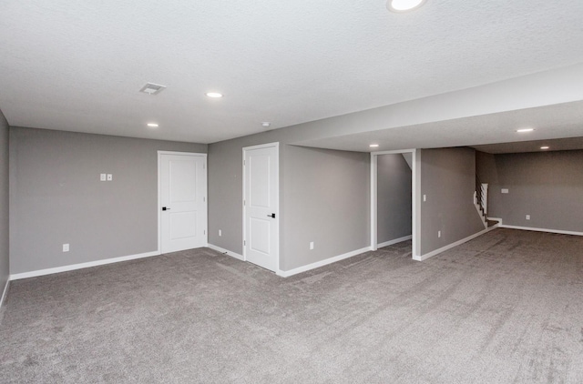 basement featuring carpet flooring and a textured ceiling