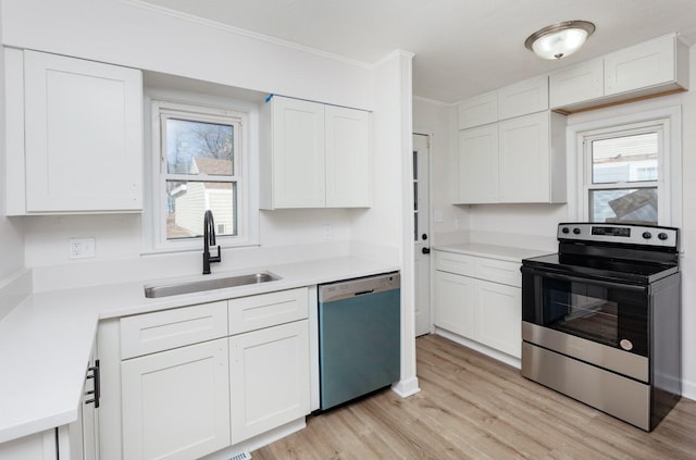 kitchen with appliances with stainless steel finishes, sink, white cabinets, ornamental molding, and light hardwood / wood-style floors