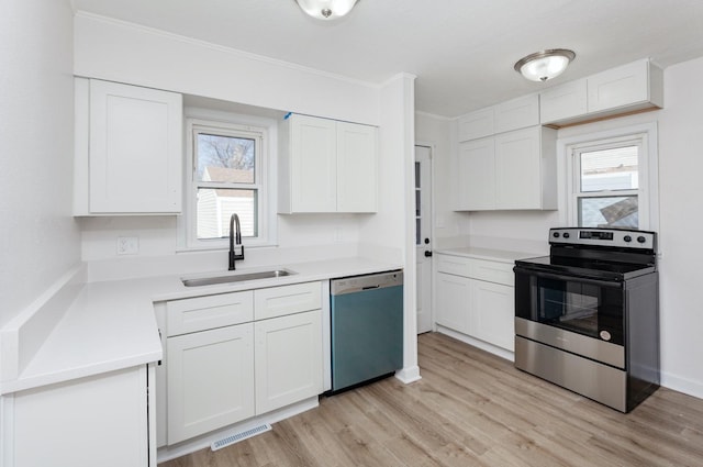 kitchen featuring sink, ornamental molding, appliances with stainless steel finishes, light hardwood / wood-style floors, and white cabinets