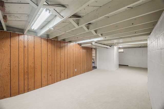 basement with carpet flooring and wood walls