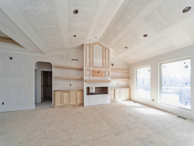 unfurnished living room with lofted ceiling and a textured ceiling